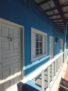 una casa azul con una puerta blanca y una ventana en Pousada Maravilha Geribá, en Búzios