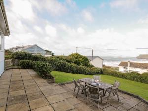 a patio with a table and chairs and the ocean at Trevega in Polzeath