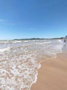 uma praia com o oceano e uma pessoa andando na água em Pousada Maravilha Geribá em Búzios