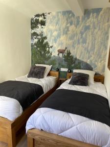 two beds in a room with a painting on the wall at CASTEL ISARD - Le Refuge in Porté-Puymorens