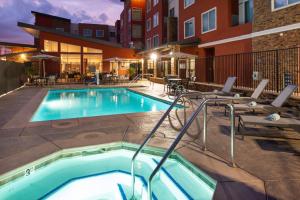 einen Pool in einem Hotel mit Tischen und Stühlen in der Unterkunft Residence Inn Visalia in Visalia