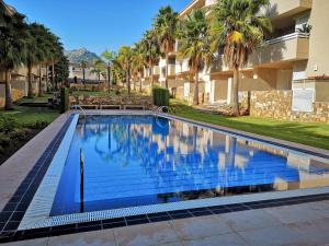 una piscina frente a un edificio con palmeras en Ático Green Paradise II, en Pego