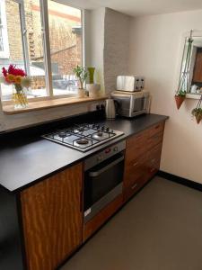 a kitchen with a stove and a microwave at Turner Cottage - 3 bed with a View of the Harbour in Margate