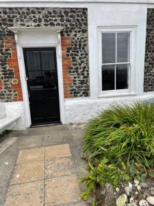 a building with a black door and two windows at Turner Cottage - 3 bed with a View of the Harbour in Margate