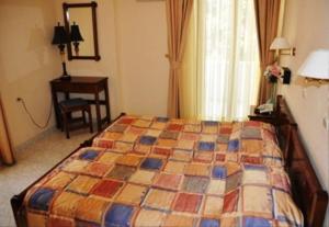 a bedroom with a bed and a desk and a window at Odyssey Hotel Apartments in Karpathos