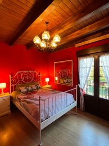 um quarto com uma cama com paredes vermelhas e um lustre em La Casa de Fefita (Stone house in a privileged environment 35 km from Bilbao) 