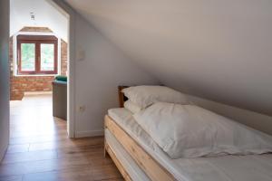 a bed with white sheets and pillows in a room at gite l'atelier du Trieu Robin in Beaumont