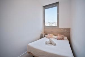 a bedroom with a white bed with a window at BcnStop Sant Pau Suites in Barcelona