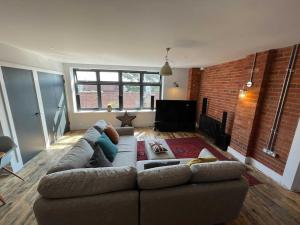 a living room with a couch and a brick wall at Luxury 1 Bedroom Apartment Lymington, New Forest in Lymington