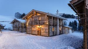 eine Blockhütte im Schnee mit eingeschaltetem Licht in der Unterkunft Schrofen Chalets in Jungholz