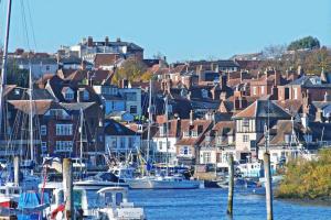 eine Gruppe von Booten, die in einem Hafen mit Häusern angedockt sind in der Unterkunft Luxury 1 Bedroom Apartment Lymington, New Forest in Lymington