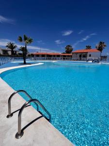 een groot zwembad met blauw water voor een gebouw bij La Casita Sun Beach in Caleta De Fuste