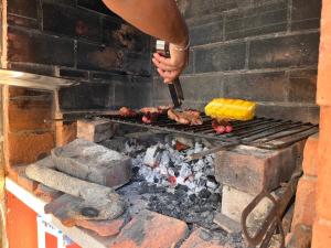 una persona está cocinando carne en una parrilla en Ericeira Destination, en Ericeira