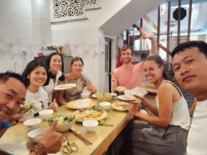 grupa ludzi siedzących przy stole jedzących jedzenie w obiekcie Sông Suối Homestay w mieście Quy Nhơn