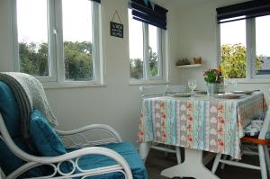 una sala da pranzo con tavolo, sedie e finestre di Bryniau Gwyrdd Chalet 11 Happy Valley a Tywyn