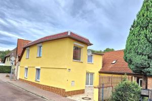uma casa amarela com um telhado vermelho numa rua em charmantes Landhaus "Wildrose", kurz vor Halle, 4 Schlafzimmer em Petersberg