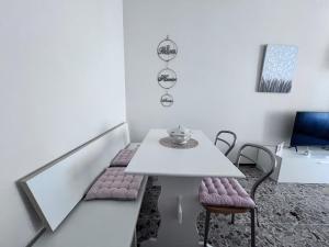 uma sala de jantar branca com uma mesa e cadeiras brancas em Casa Piemont em Casale Monferrato