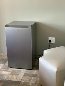 a silver refrigerator in a room with a stool at Orlando Manor in Soweto