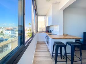 een keuken met een aanrecht en krukken en een groot raam bij Phaedrus Living: Ourania City Heights Flat in Limassol