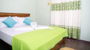 a bedroom with a bed with a green blanket and a window at Airport Villa D 87 in Katunayaka