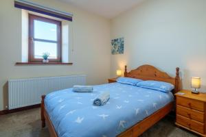 a bedroom with a bed with a blue comforter at Farm Cottage - Kirkby-In-Furness, ideal for the Central Lake District in Soutergate