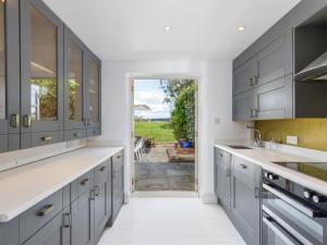 uma cozinha com armários cinzentos e uma porta para um quintal em The Courtyard em Pulborough