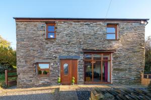a stone cottage with a wooden door and windows at Farm Cottage - Kirkby-In-Furness, ideal for the Central Lake District in Soutergate