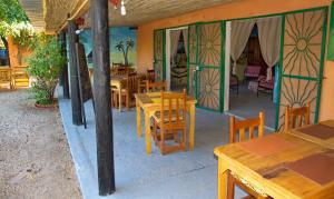Auberge Plein Soleil في Mbodiène: مطعم بطاولات وكراسي خشبية ونوافذ زجاجية ملطخة