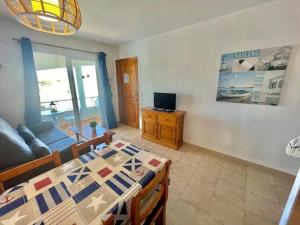 Turqueta - Apartamento con piscina junto la playa في كالا إن بلانيس: غرفة معيشة مع طاولة طعام وتلفزيون