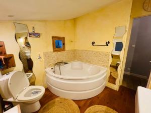 La salle de bains est pourvue d'une baignoire blanche et de toilettes. dans l'établissement Petite Maison des Renaudins, à Taillebourg