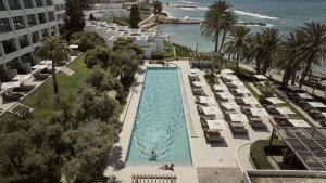 una vista aérea de una piscina con sillas y el océano en Almyra, en Pafos