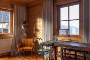 um quarto com uma mesa e cadeiras de madeira e janelas em Almgasthof Windischgrätz em Bad Gastein