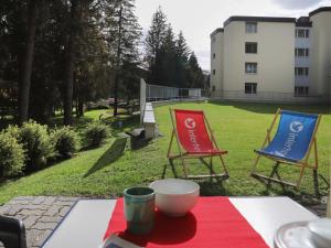 zwei Stühle auf einem Tisch im Garten in der Unterkunft Apartment Allod Park Haus B E01 by Interhome in Davos
