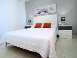a white bedroom with a large white bed with red pillows at Apartment Zafiro 02 by Interhome in Calpe
