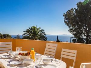 a table with plates and bowls of food on a balcony at Apartment Cadet Rousse by Interhome in Le Lavandou