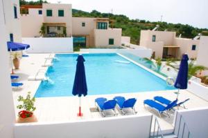 a swimming pool with blue chairs and umbrellas at Plakoti Village in Maroulás