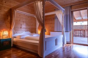 sypialnia z łóżkiem z baldachimem w drewnianym pokoju w obiekcie Almgasthof Windischgrätz w mieście Bad Gastein