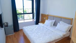 a bedroom with a white bed with a large window at PALM VILLAGE BUSINESS HOTEL in Dar es Salaam