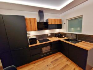 a kitchen with black cabinets and wooden counters at -Le Zen Spa+Jacuzzi+Parking+Clim in Colmar