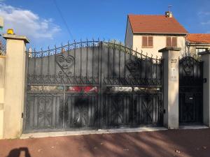 a black gate with hearts on it in front of a house at La Maison des roses in Nanterre