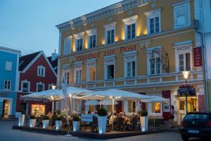 um restaurante em frente a um edifício com mesas e guarda-sóis em Hotel Gasthof zur Post em Obernberg am Inn