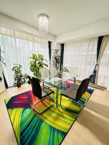 a dining room with a glass table and chairs on a colorful rug at Pure Luxury Residence in Timişoara