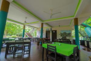 ein Esszimmer mit grünen Tischen und Stühlen in der Unterkunft The Green Heaven Resort in Sigiriya