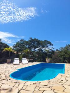 a swimming pool with two chairs and a blue pool at Shanti Life in Búzios