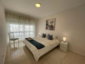 une chambre avec un grand lit et une chaise dans l'établissement Villa Dona Rosa - Viana do Castelo, à Viana do Castelo