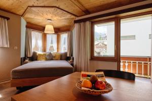 una camera da letto con un letto e un tavolo con una ciotola di frutta di Hotel Simi a Zermatt Altre 37 foto