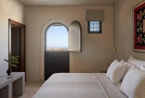 a bedroom with a bed and an arched window at Askianos Luxury Villas - An Oasis of Harmony & Elegance in Lístaros