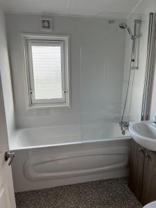 y baño con bañera blanca y lavamanos. en Stunning 4 Berth Lodge With Decking At Manor Park In Hunstanton Ref 23173k en Hunstanton