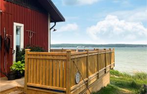 にあるAwesome Home In Vikbolandet With House Sea Viewの水際の木塀付き赤い家