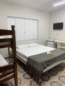 a bedroom with a bed and a tv and a chair at Pousada Olívia in São Pedro da Aldeia